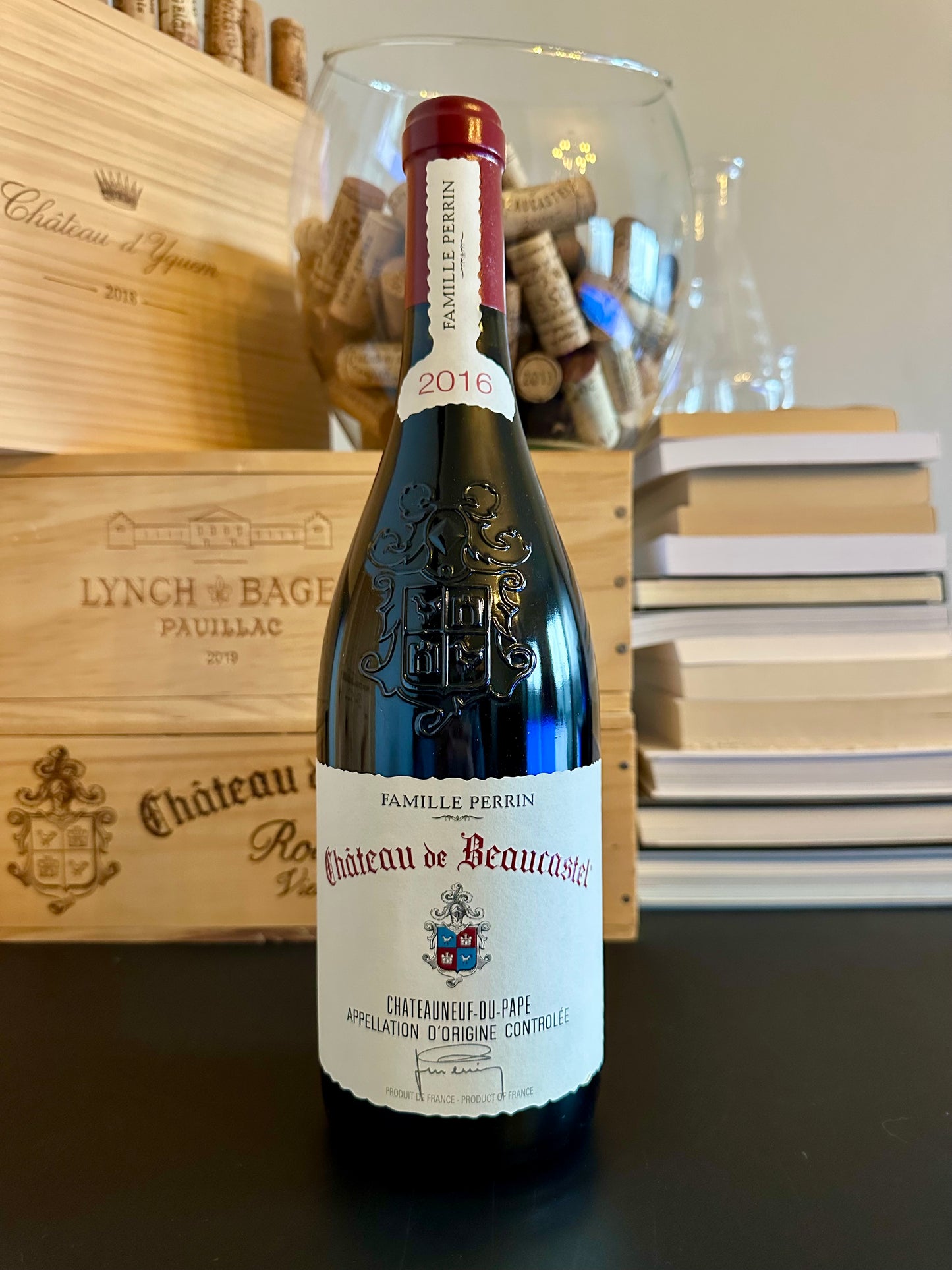 Wine bottle of Château de Beaucastel 2016 in front of wooden wine boxes.
