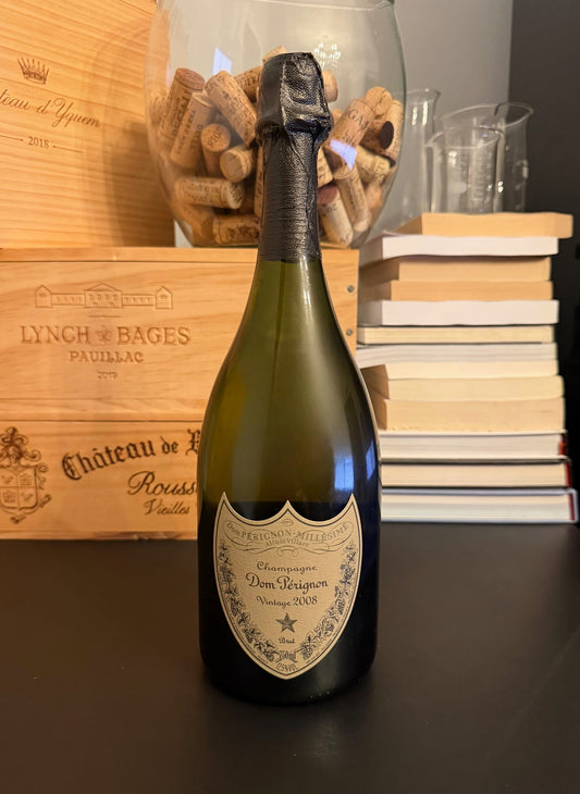 Bottle of Dom Pérignon Vintage 2008 Champagne with a wooden box and books in the background