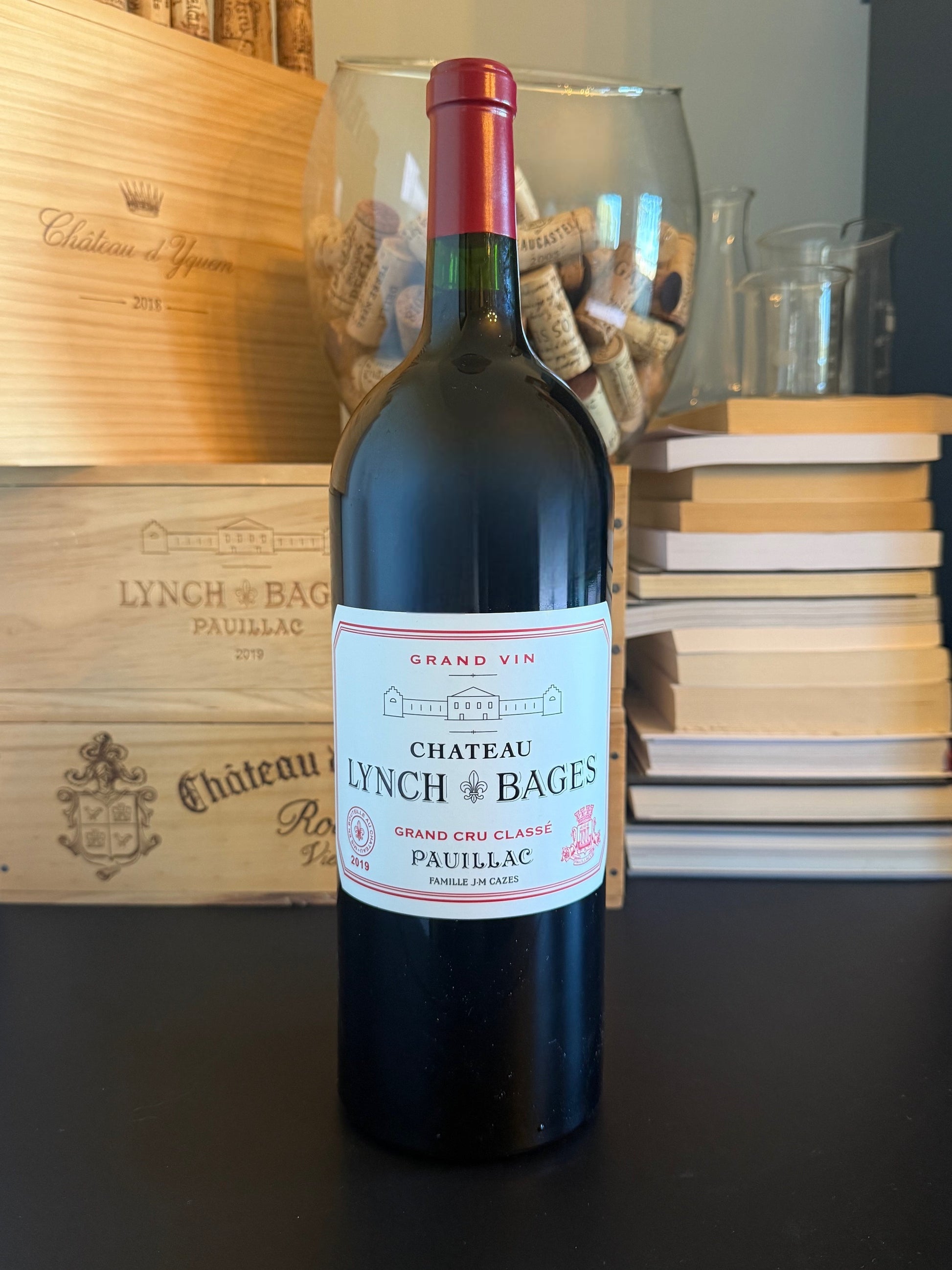 Bottle of Chateau Lynch Bages 2019 Magnum with a wooden box and books in the background