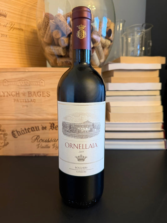 Bottle of Ornellaia Bolgheri Superiore 2019 with a wooden crate and books in the background.
