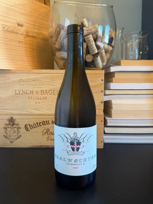 Wine bottle Weingut Carsten Saalwächter Chardonnay R 2022 in front of wooden wine boxes and a cork container.