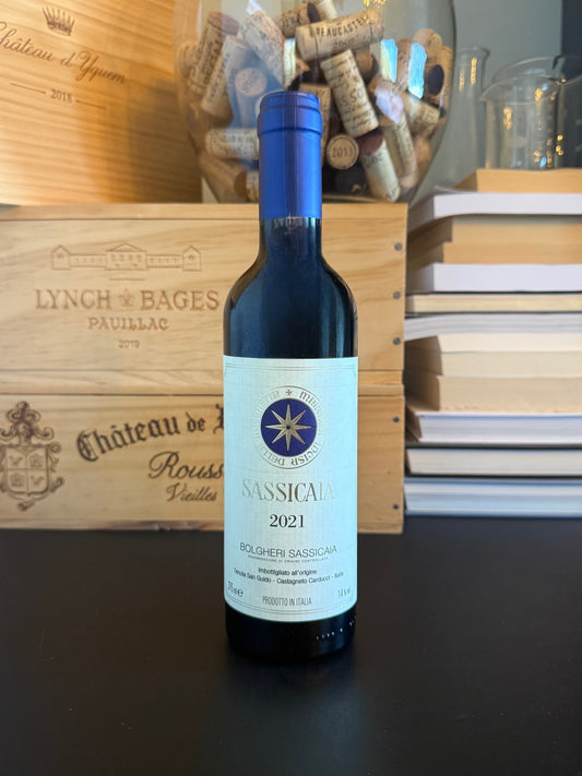 Wine bottle Sassicaia 2021 demi-bouteille with wine-related items in the background.