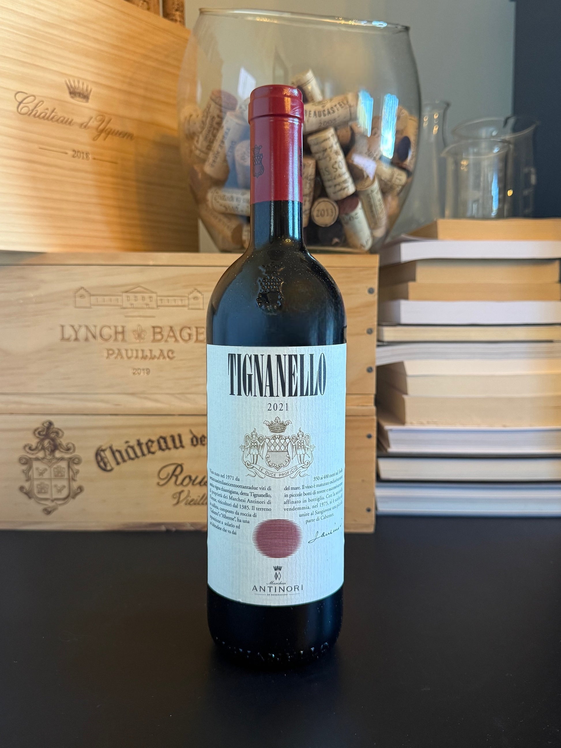 Bottle of Tignanello 2021 wine with a wooden wine box and corks in the background.