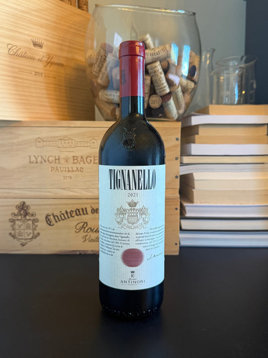 Bottle of Tignanello 2021 wine with a wooden wine box and corks in the background.
